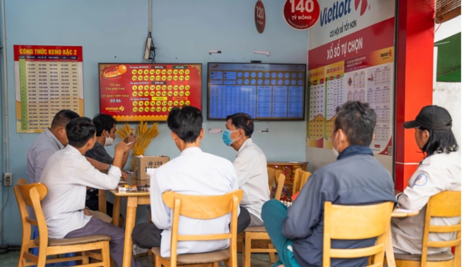 Đông đảo người chơi nán lại điểm bán hàng để dò số Keno trực tiếp qua màn hình lớn. Ảnh: Vietlott